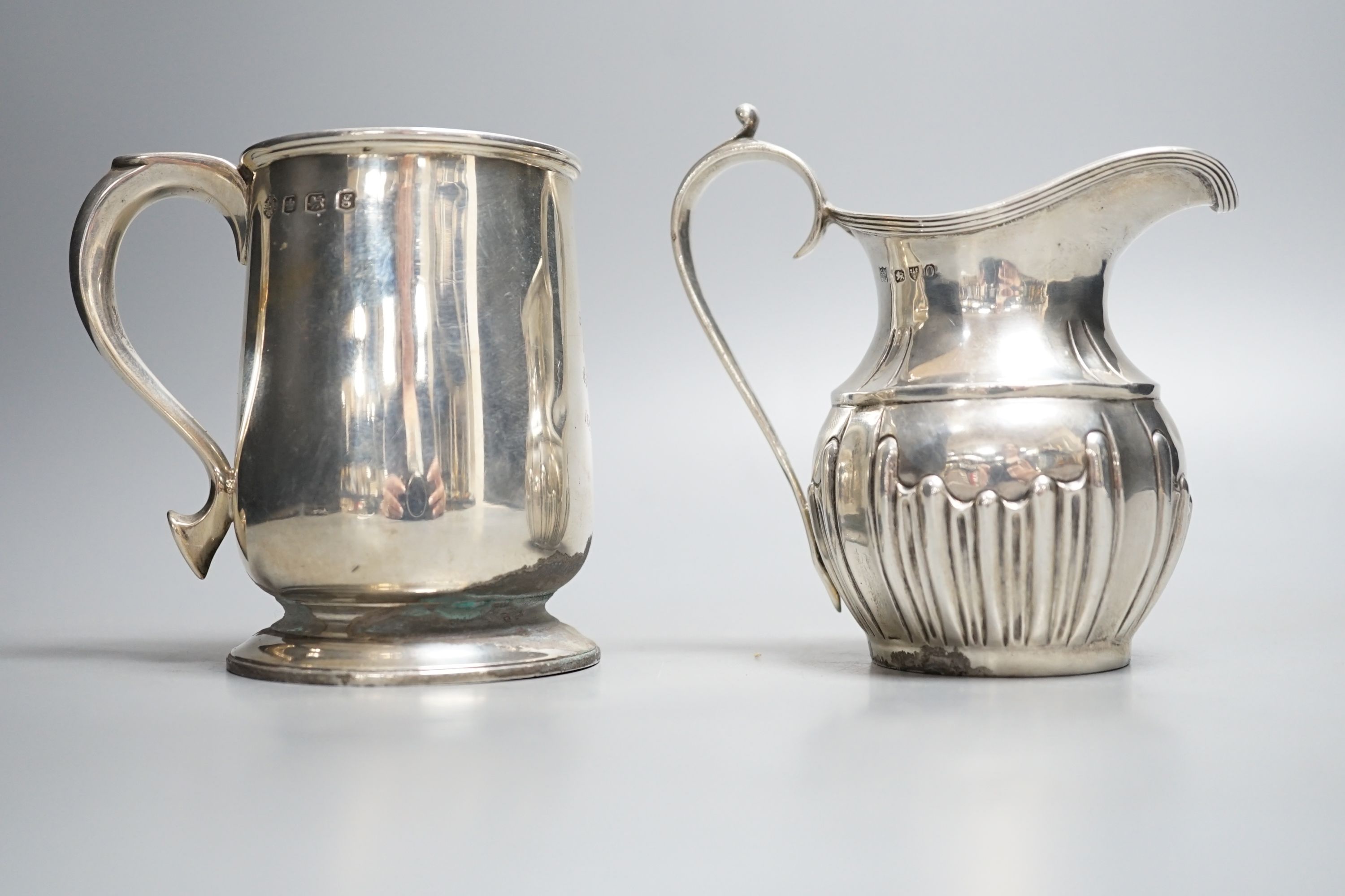 A late Victorian silver cream jug, Nathan & Hayes, Chester, 1897 and a George V silver christening mug, William Hutton & Sons, Sheffield, 1924